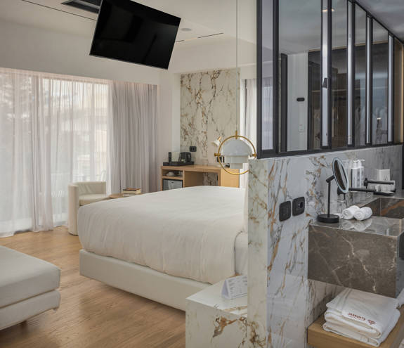 Ethereal White Resort Heraklion Luxury Suite washbasin and the double bed in the other side of the wall