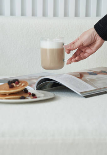 Ethereal White Resort Heraklion cup of coffee, an open magazine and a plate of pancakes