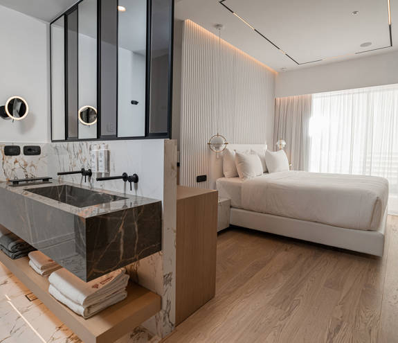 Ethereal White Resort Heraklion Deluxe Suite washbasins and the double bed in the background